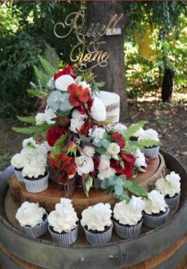 naked wedding cake with fresh flowers and cupcakes