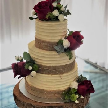 buttercream wedding cake with beautiful full red roses and hession ribbon