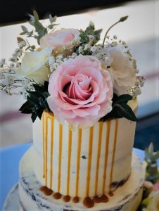 3 tier semi naked wedding cake with caramel dripping with white and pink fresh flowers by rimma's wedding cakes perth